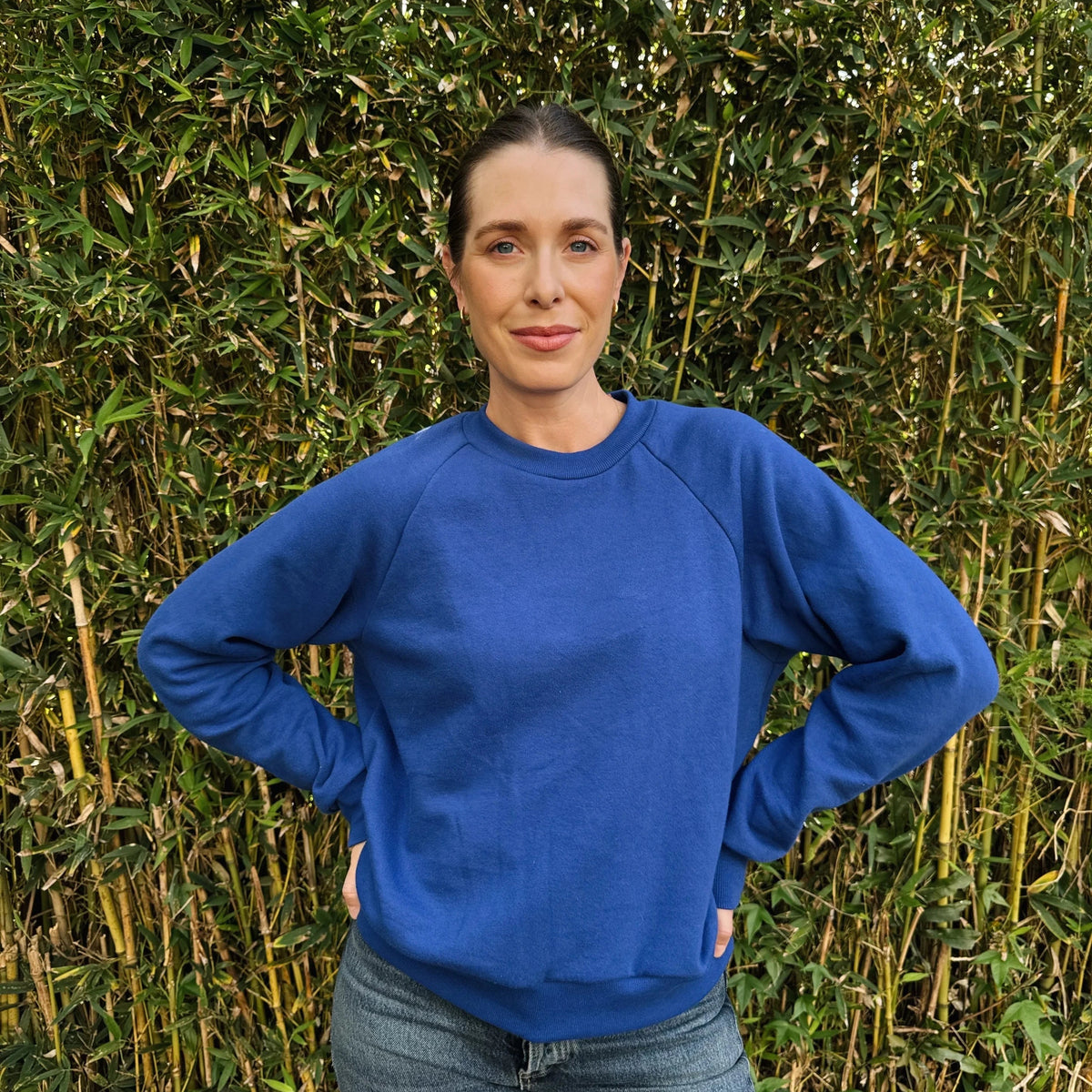 Woman wearing a blue sweater standing in front of a bamboo wall